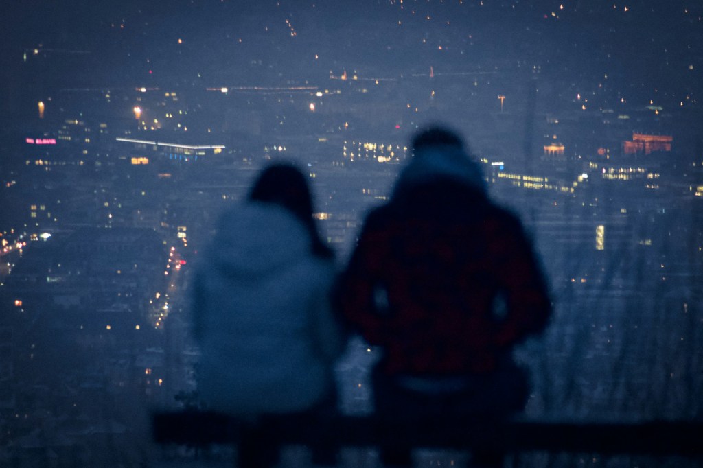 Silhouetted couple sitting together overlooking a city at night, representing healing after infidelity, betrayal trauma, and relationship repair.